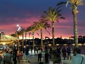 a crowd of people standing near a beach with palm trees at Appartamenti Luxury Greco in Brindisi