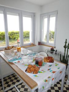 a table with food on it in a kitchen with windows at "Lumière du Cap" vue mer B&B à la VILLA PLEIN VENT in Barneville-Carteret