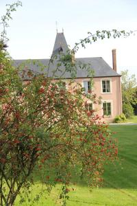 una casa con un árbol con bayas rojas delante de ella en Chambres d'hôtes La Verrerie du Gast, en Tanville