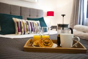 ein Tablett mit Speisen und Getränken auf dem Bett in der Unterkunft Urban Living's - The Burley Luxury City Apartment in Oxford