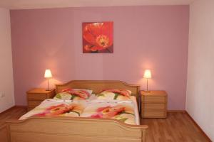 1 dormitorio con 1 cama con 2 lámparas y una pintura floral en Ferienwohnung Zu den Weinbergen, en Traustadt