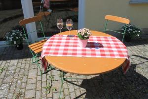 una mesa con dos copas de vino y flores. en Ferienwohnung Zu den Weinbergen, en Traustadt