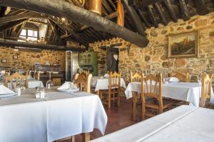 un restaurante con mesas y sillas blancas en una habitación en O Palleiro do Pe do Forno, en Orellán