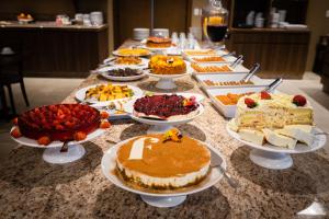 uma mesa com muitos tipos diferentes de bolos e sobremesas em Hotel Fioreze Primo em Gramado