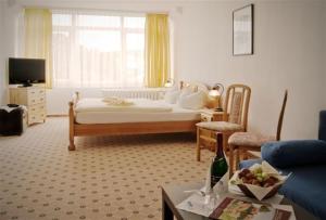 a bedroom with a bed and a living room at Landhotel Harz in Thale