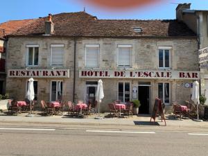 a hotel with tables and chairs in front of a building at L'Escale in Longeau