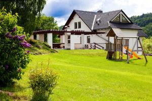 a white house with a yard with a grass field at Vila Element in Jeseník
