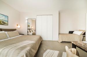 a white bedroom with two beds and a mirror at Garda Room in Peschiera del Garda