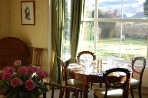 uma sala de jantar com uma mesa com flores e uma janela em The Old Vicarage Dolfor em Newtown