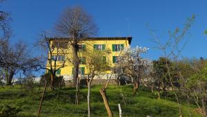 żółty budynek na szczycie wzgórza z drzewami w obiekcie Villa Maria w mieście Mignanego