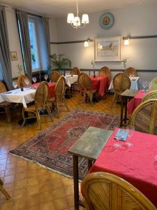 a dining room with tables and chairs with red table cloth at L'Escale in Longeau