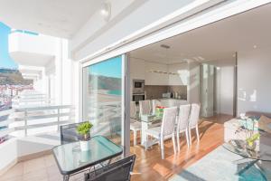 a living room with a glass table and a kitchen at Nazare Marisol Praia in Nazaré