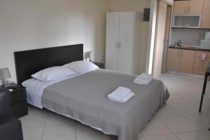 a bedroom with a large bed with two towels on it at AVR Airport Deluxe Suites 4 in Markopoulo