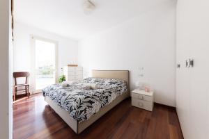 biała sypialnia z łóżkiem i krzesłem w obiekcie Oasi w Bergamo