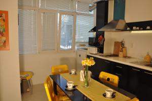 una cocina con sillas amarillas y una mesa con flores. en Arlequin Apartment, en Varna