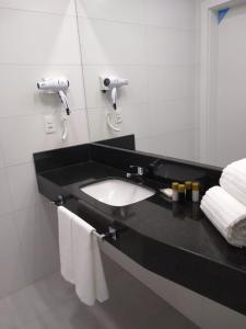 a bathroom with a black counter with a sink and towels at Tri Hotel Executive Indaial in Indaial