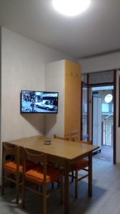 a dining room table with chairs and a tv on the wall at Appartamento al mare Lorella in Sottomarina