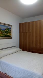 Schlafzimmer mit einem weißen Bett und einem Holzschrank in der Unterkunft Appartamento al mare Lorella in Sottomarina