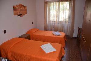 2 bedden in een hotelkamer met oranje lakens bij Casa Vacanze Ester in Brenzone sul Garda