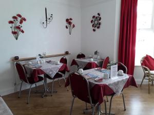 een eetkamer met 2 tafels en rode gordijnen bij Merriedale Guest House in Paignton