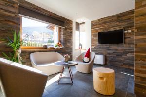 uma sala de estar com um sofá e uma cadeira e uma televisão em Residence Mille Montagne em Andalo