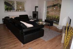 a living room with a black couch and a table at Ferienwohnungen TalBach in Simmerath