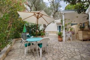 a patio with a table and chairs and an umbrella at Room Milka in Veli Lošinj