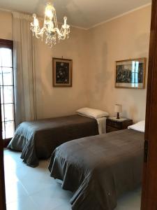 2 bedden in een kamer met een kroonluchter bij La casa di Fausto in Cesarò