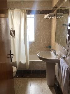 a bathroom with a shower, sink, and tub at Hotel Ulveira in Oliveira de Frades