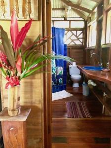 a bathroom with a toilet and a vase of flowers at Las Ranitas in Puerto Viejo