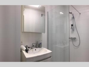 a white bathroom with a sink and a shower at DUINLICHT-Oostduinkerke in Oostduinkerke