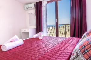 a bedroom with a pink bed with towels and a balcony at Apartments Family Roso in Promajna