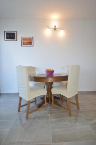 una mesa con sillas blancas y un bol de fruta en ella en Marija, en Betina