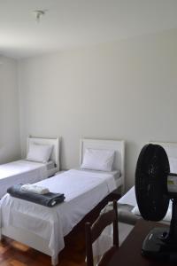a room with two beds and a desk with a fan at Hospedagem Solar do Rosário in Diamantina