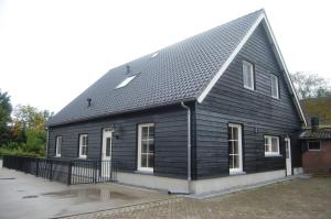 a black house with a gambrel roof at Toenders in Wintelre