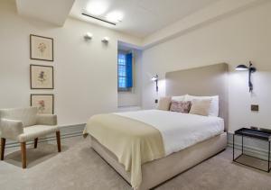 a bedroom with a large bed and a chair at 10 Strait Street Apartments in Valletta