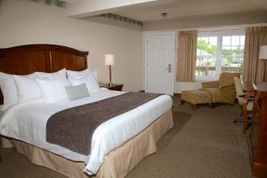 a hotel room with a large bed and a chair at Holiday Hill Inn & Suites in Dennis Port