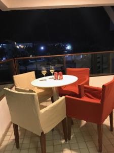 un tavolo con sedie e bicchieri da vino sul balcone di FLAT 6206F - ANCORAR RESORT a Porto De Galinhas