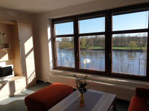 uma sala de estar com grandes janelas com vista para um lago em Ferienwohnung am Hohen Elbufer em Coswig