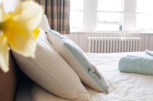 a bed with white pillows and a yellow flower on it at Murray Library Hostel in Anstruther