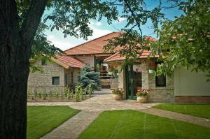 una casa de ladrillo con un patio con césped verde en BÉNI family wine farm, en Cegléd