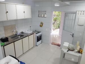 eine weiße Küche mit Spüle und Herd in der Unterkunft Casa dentro de Porto de Galinhas. 04Suítes.01Quarto. in Porto De Galinhas