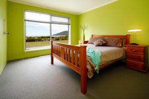Schlafzimmer mit grünen Wänden und einem Bett mit Fenster in der Unterkunft Sisters Beach Retreat in Sisters Beach