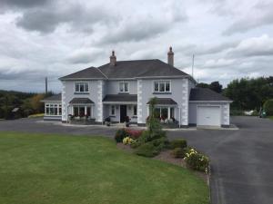 a large white house with a driveway at Colmán House in Kilmihil