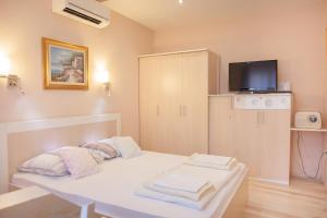 Una pequeña habitación con una cama blanca y un televisor. en Ba & Bo, en Šibenik