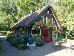 een klein huis met een rode deur en een patio bij B&B Kupershof in Epe