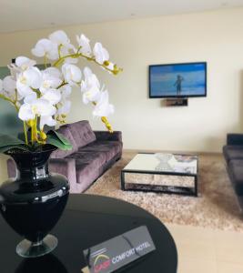 a black vase with white flowers on a table in a living room at Cast Comfort Hotel in Paranaíba