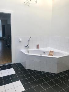 a white tub in a bathroom with a black tile floor at GUESTHOUSE UIT DE KUNST in Leeuwarden