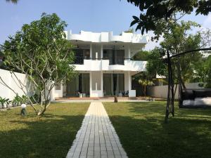 ein großes weißes Haus mit Rasen davor in der Unterkunft villa layanga - riverside guestrooms in Aluthgama
