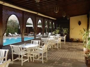 un patio con mesas blancas y sillas junto a una piscina en Riad Zahra, en Essaouira